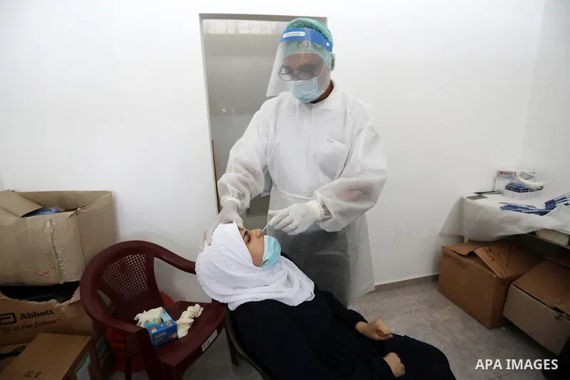 A Palestinian health worker collects a swab sample from a person for Covid-19 test, at a temporary vaccination centre set up in Khan Younis in the southern Gaza Strip on August 23, 2021. Palestinian health officials on M...