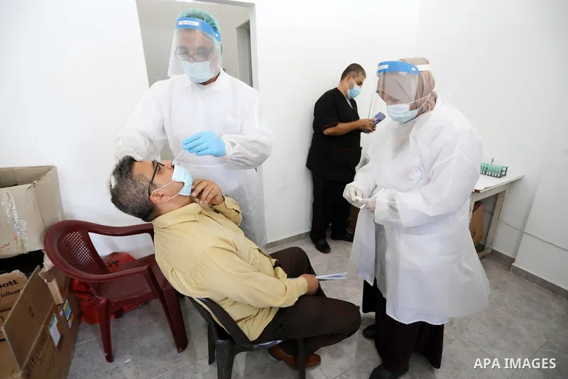 A Palestinian health worker collects a swab sample from a person for Covid-19 test, at a temporary vaccination centre set up in Khan Younis in the southern Gaza Strip on August 23, 2021. Palestinian health officials on M...