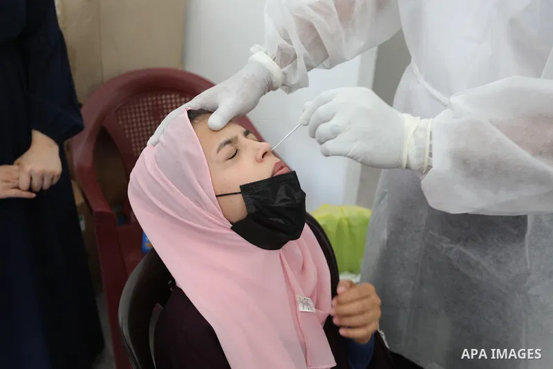 A Palestinian health worker collects a swab sample from a person for Covid-19 test, at a temporary vaccination centre set up in Khan Younis in the southern Gaza Strip on August 23, 2021. Palestinian health officials on M...