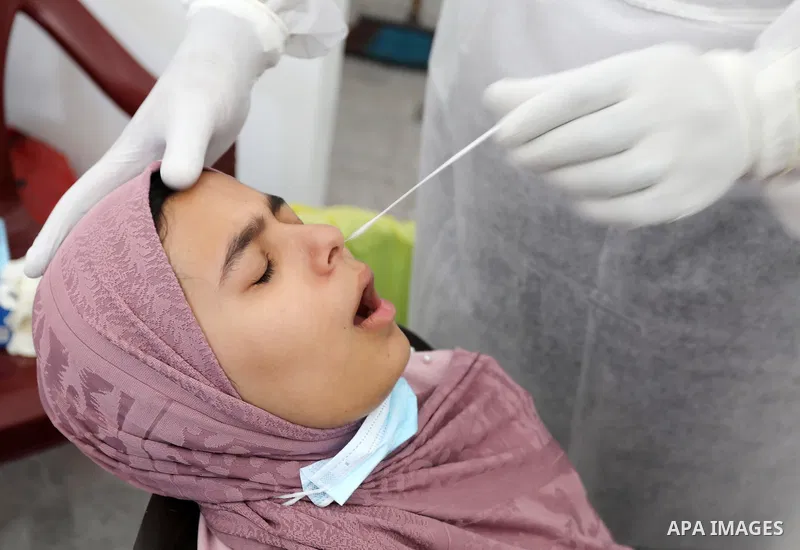 A Palestinian health worker collects a swab sample from a person for Covid-19 test, at a temporary vaccination centre set up in Khan Younis in the southern Gaza Strip on August 23, 2021. Palestinian health officials on M...