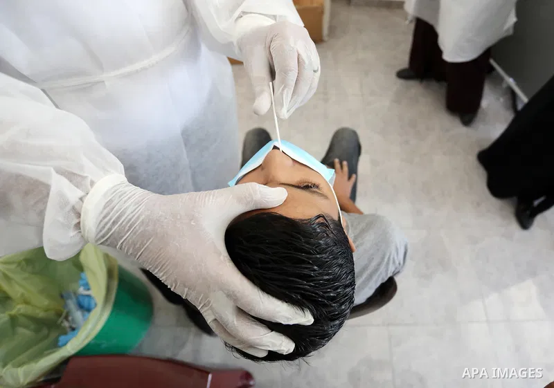 A Palestinian health worker collects a swab sample from a person for Covid-19 test, at a temporary vaccination centre set up in Khan Younis in the southern Gaza Strip on August 23, 2021. Palestinian health officials on M...