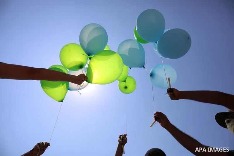 Masked Palestinians prepare incendiary balloons near Al-Bureij camp, in the center of the Gaza Strip on August 24, 2021. The Israel Forces carried out airstrikes in the Gaza Strip late Monday night in response to the lau...