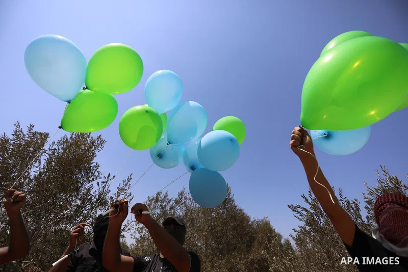Masked Palestinians prepare incendiary balloons near Al-Bureij camp, in the center of the Gaza Strip on August 24, 2021. The Israel Forces carried out airstrikes in the Gaza Strip late Monday night in response to the lau...