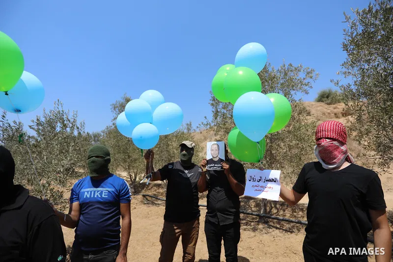 Masked Palestinians prepare incendiary balloons near Al-Bureij camp, in the center of the Gaza Strip on August 24, 2021. The Israel Forces carried out airstrikes in the Gaza Strip late Monday night in response to the lau...