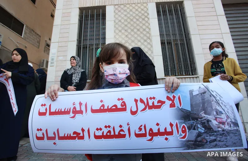 Palestinian relatives of orphans and disabled hold banners during a protest against Banks policy on the closure of the accounts of charities in Gaza city on August 25, 2021. The fiscal position in Gaza strip has worsened...