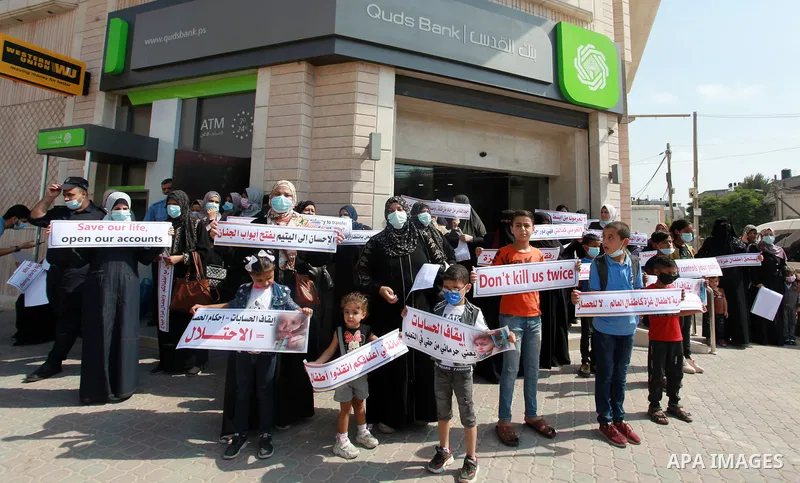 Palestinian relatives of orphans and disabled hold banners during a protest against Banks policy on the closure of the accounts of charities in Gaza city on August 25, 2021. The fiscal position in Gaza strip has worsened...