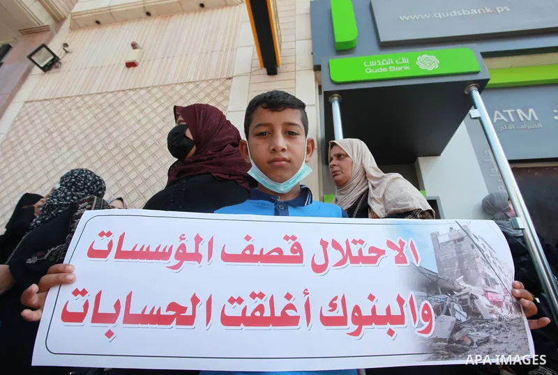 Palestinian relatives of orphans and disabled hold banners during a protest against Banks policy on the closure of the accounts of charities in Gaza city on August 25, 2021. The fiscal position in Gaza strip has worsened...