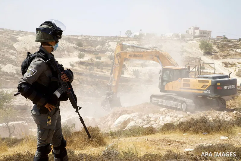 An Israeli bulldozer demolishes a Palestinian agricultural piece of land in area (C), in the West Bank town of Hebron, on August 25, 2021, which according to Israel were built without authorisation in "Area C" of the Wes...