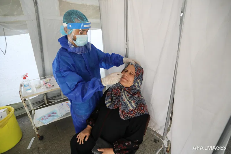 A Palestinian health worker collects a swab sample from a person for Covid-19 test, at a temporary vaccination centre set up, in Deir Al Balah in the center of Gaza strip on August 26, 2021. Three people have died of cor...