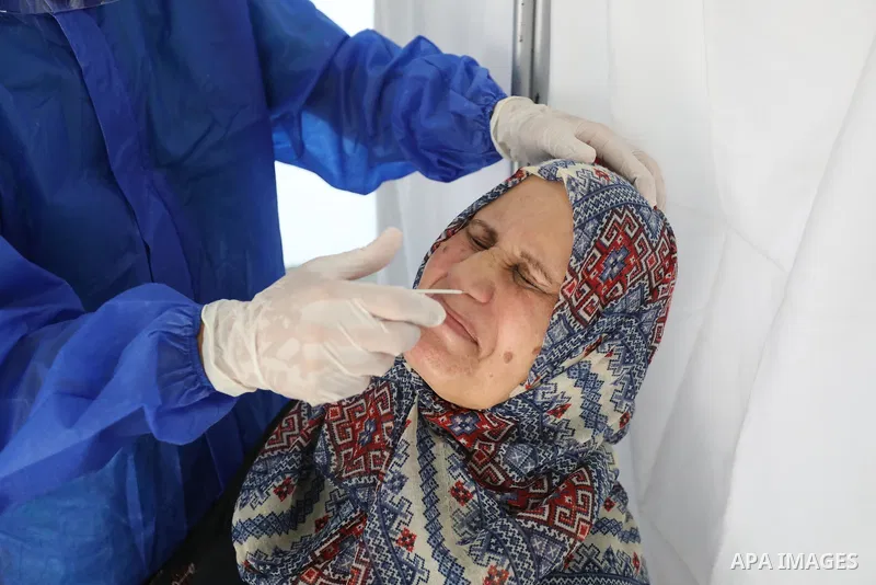 A Palestinian health worker collects a swab sample from a person for Covid-19 test, at a temporary vaccination centre set up, in Deir Al Balah in the center of Gaza strip on August 26, 2021. Three people have died of cor...