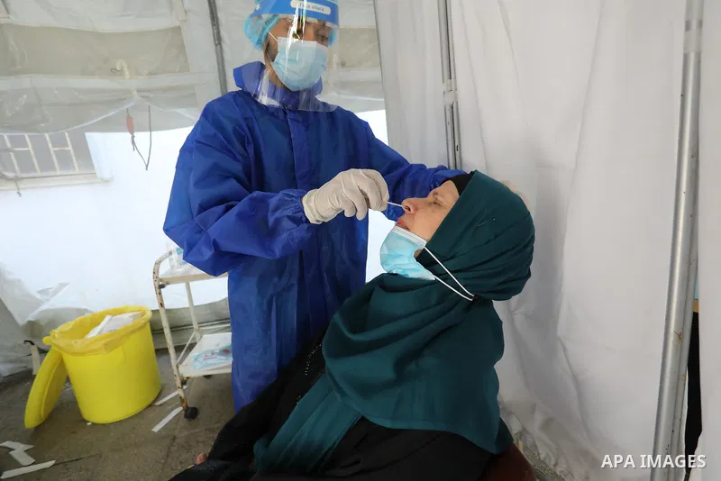 A Palestinian health worker collects a swab sample from a person for Covid-19 test, at a temporary vaccination centre set up, in Deir Al Balah in the center of Gaza strip on August 26, 2021. Three people have died of cor...
