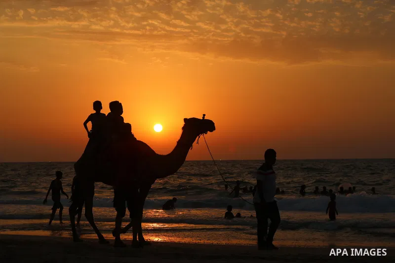 Palestinians gather at the beach in the Mediterranean Sea in Deir al-Balah in the center of Gaza Strip on August 27, 2021. The beach is one of the few open public spaces in this densely populated city. Photo by Ashraf Am...