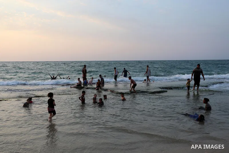 Palestinians gather at the beach in the Mediterranean Sea in Deir al-Balah in the center of Gaza Strip on August 27, 2021. The beach is one of the few open public spaces in this densely populated city. Photo by Ashraf Am...