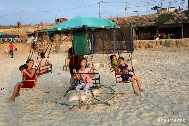 Palestinians gather at the beach in the Mediterranean Sea in Deir al-Balah in the center of Gaza Strip on August 27, 2021. The beach is one of the few open public spaces in this densely populated city. Photo by Ashraf Am...