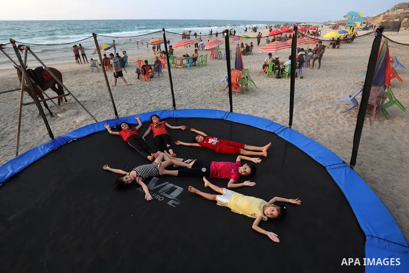Palestinians gather at the beach in the Mediterranean Sea in Deir al-Balah in the center of Gaza Strip on August 27, 2021. The beach is one of the few open public spaces in this densely populated city. Photo by Ashraf Am...