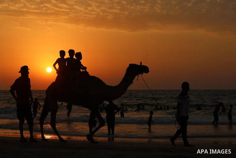 Palestinians gather at the beach in the Mediterranean Sea in Deir al-Balah in the center of Gaza Strip on August 27, 2021. The beach is one of the few open public spaces in this densely populated city. Photo by Ashraf Am...