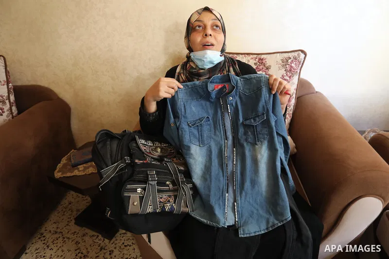 The mother of Palestinian teen Omar Abu Neal displays his school clothes during his funeral in Gaza city on August 28, 2021. A 13-year-old Gaza boy who was shot and seriously wounded by Israeli soldiers last week has die...