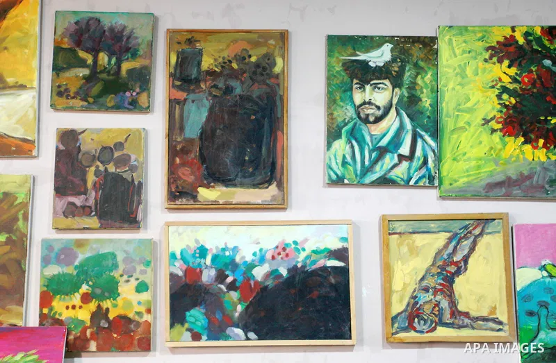 Palestinian plastic artists Mohammed Al-Hawajri and his wife Dina Matar set up an exhibition of their paintings on the roof of their house in Al-Bureij refugee camp in the center of Gaza strip, on August 28, 2021. The tw...