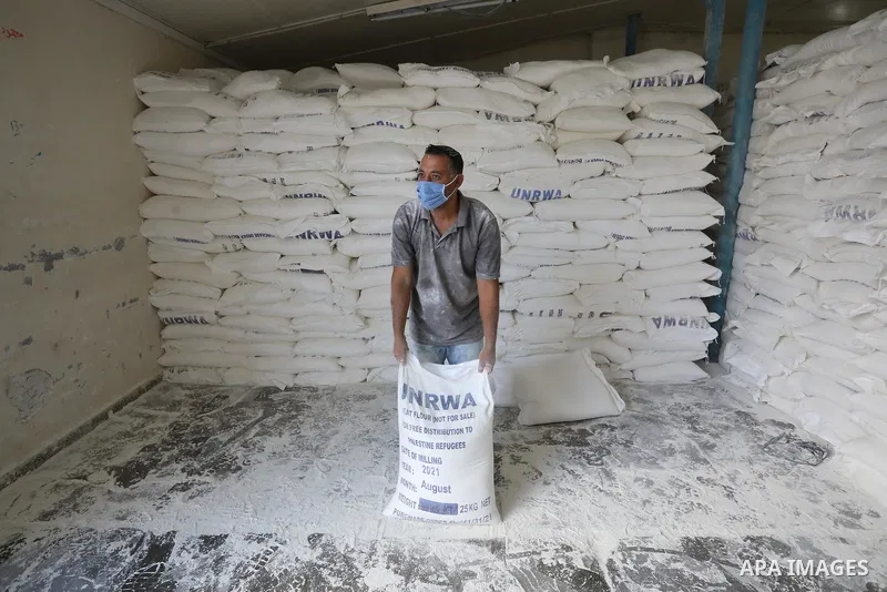 Palestinian employees at the United Nations Relief and Works Agency for Palestinian Refugees (UNRWA) wearing protective masks and gloves, prepare food aid rations for refugees, in Dair Al Balah in the center of Gaza stri...
