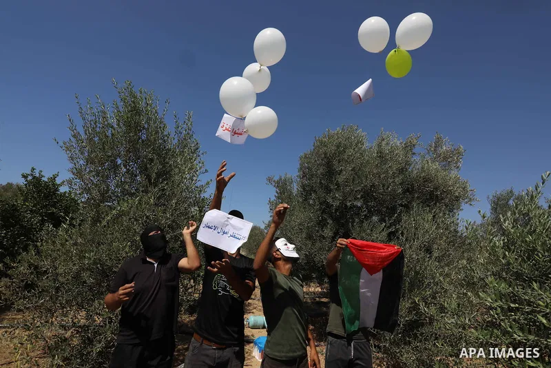 Masked Palestinians prepare incendiary balloons near Jabalia in the northern of Gaza Strip, on September 4, 2021. Reports in Palestinian media indicated that units in charge of incendiary balloon attacks on Israeli plann...