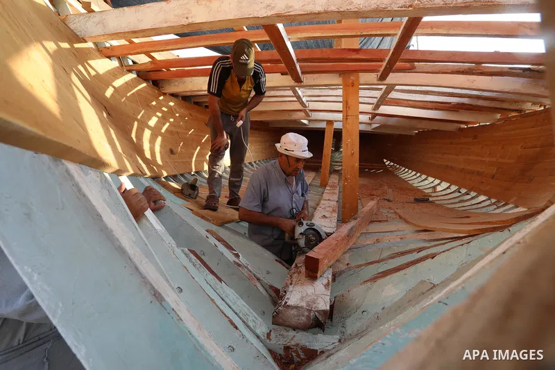 Palestinians work on the largest fishing boat in Khan Yunis in the southern of Gaza Strip, on September 5, 2021. Palestinians made the largest fishing boat in the Gaza Strip, 21 meters long and 6 meters wide, with simple...