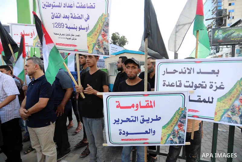 Palestinians hold placadrs during a rally on the occasion of the 28th anniversary of the Oslo accords between Palestinians and Israel, in Gaza city on September 13, 2021. In 1993, Israeli Prime Minister Yitzhak Rabin and...