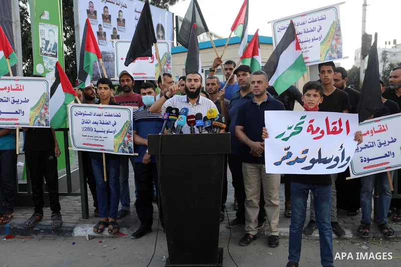 Palestinians hold placadrs during a rally on the occasion of the 28th anniversary of the Oslo accords between Palestinians and Israel, in Gaza city on September 13, 2021. In 1993, Israeli Prime Minister Yitzhak Rabin and...