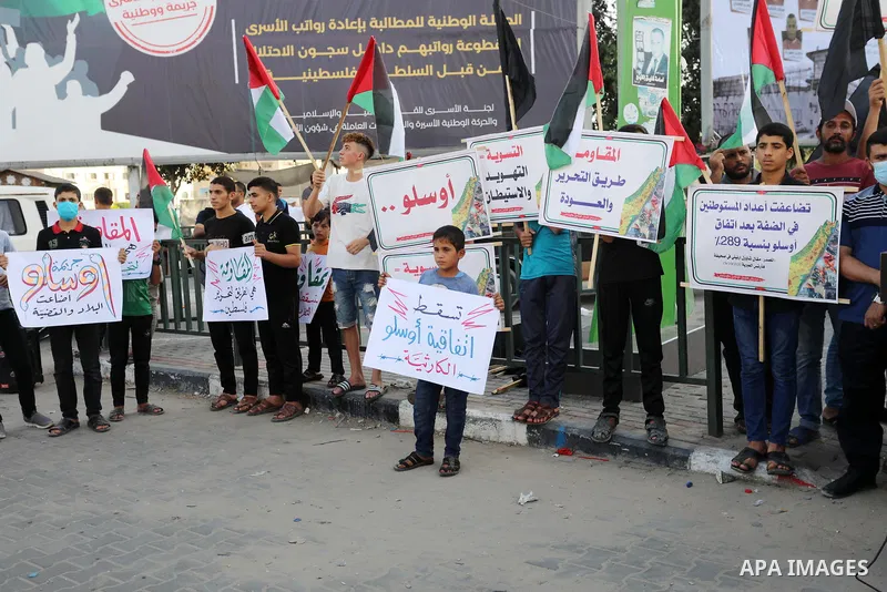 Palestinians hold placadrs during a rally on the occasion of the 28th anniversary of the Oslo accords between Palestinians and Israel, in Gaza city on September 13, 2021. In 1993, Israeli Prime Minister Yitzhak Rabin and...