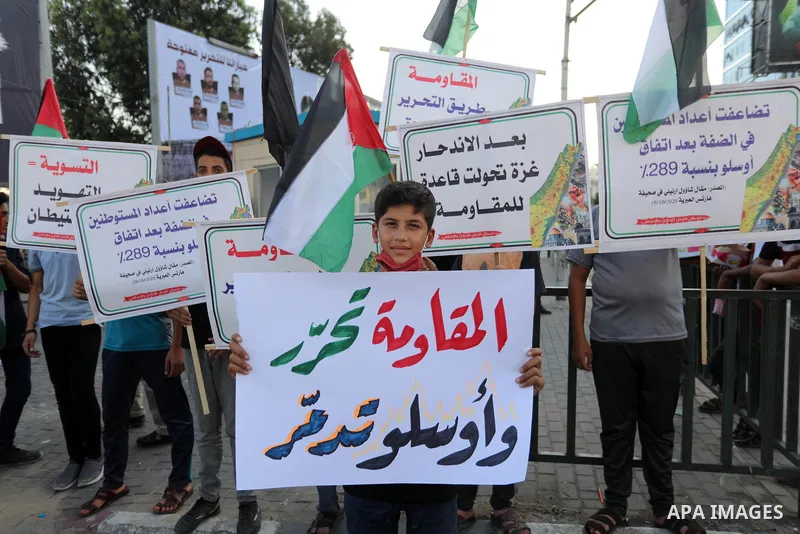 Palestinians hold placadrs during a rally on the occasion of the 28th anniversary of the Oslo accords between Palestinians and Israel, in Gaza city on September 13, 2021. In 1993, Israeli Prime Minister Yitzhak Rabin and...