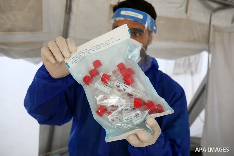 A Palestinian health worker collects a swab sample from a person for Covid-19 test, at a temporary vaccination centre set up, in Deir al-Balah in the center of Gaza Strip on September 15, 2021. COVID-19 claimed the life...