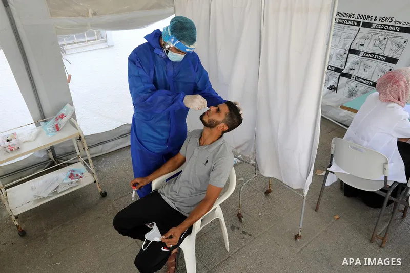 A Palestinian health worker collects a swab sample from a person for Covid-19 test, at a temporary vaccination centre set up, in Deir al-Balah in the center of Gaza Strip on September 15, 2021. COVID-19 claimed the life...
