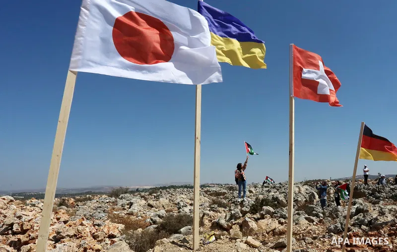 Palestinian activists raise the flags of nations, that oppose illegal settlements at the newly erected camp dubbed the United Nations camp, near the Israeli settlement of Ariel, west of West Bank town of Salfit on Septem...