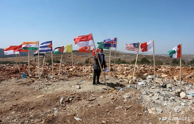 Palestinian activists raise the flags of nations, that oppose illegal settlements at the newly erected camp dubbed the United Nations camp, near the Israeli settlement of Ariel, west of West Bank town of Salfit on Septem...