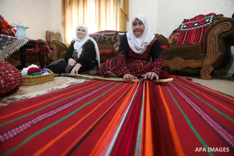 Palestinian women weave the traditional products, wool ornaments and carpets in the West Bank city of Hebron on September 23, 2021. Weaving sheep's wool into traditional carpets is one oldest professions, it takes skill,...