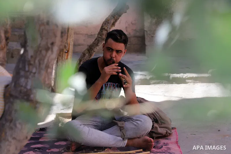 Palestinian youth Mohamed Hamida, 20, makes a musical instrument Yrgoul, in Beit Hanoun in the northern Gaza Strip, on September 27, 2021. The yrgoul instrument is an ancient Palestinian folk instrument, also known as th...