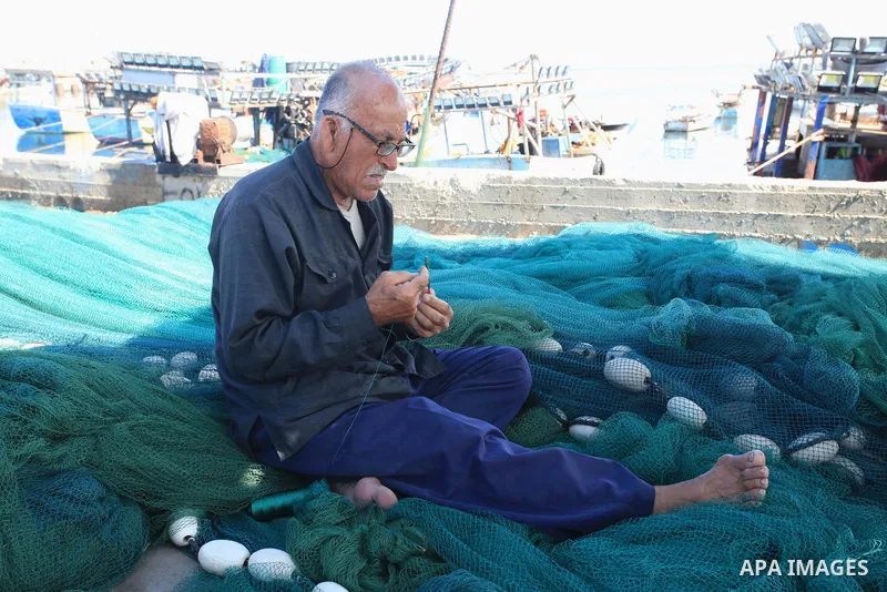 Palestinian fisherman, Rashad Al-Hassi, 77, works on his fishing net, at Gaza seaport, on October 2, 2021. The International Day of Older Persons is observed on October 1 each year. Being a fisherman in Gaza means to pra...