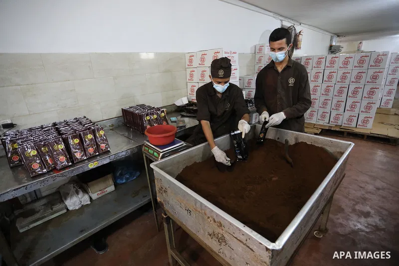 Palestinian men work at a coffee factory in Gaza city on October 6, 2021. 6 tons of coffee are consumed in Gaza strip daily. More than six different companies compete in the coffee production business in Gaza. The increa...