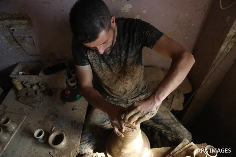 A Palestinian pottery worker makes earthenware vases at a pottery workshop in the West Bank city of Hebron on 07 October 2021. Pottery is a very ancient and traditional industry in Hebron. It has been known since more th...
