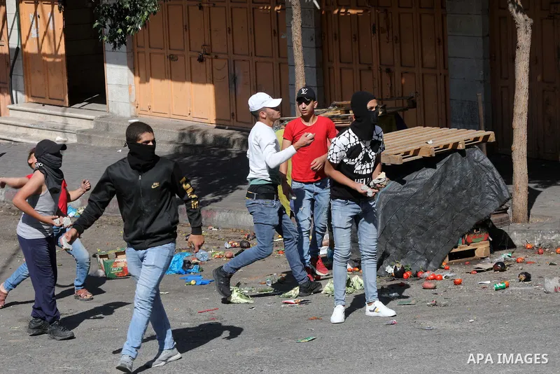 Palestinian protesters hurl stones towards Israeli troops during clashes in the West Bank city of Hebron, on October 8, 2021. Photo by Mamoun Wazwaz