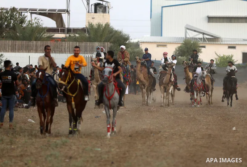 Palestinians ride horses and camels during a local race, in Nuseirat, in the center of Gaza strip on October 8, 2021. Breeders of Arabian horses in Gaza have been struggling to secure the necessary medicines and vaccinat...