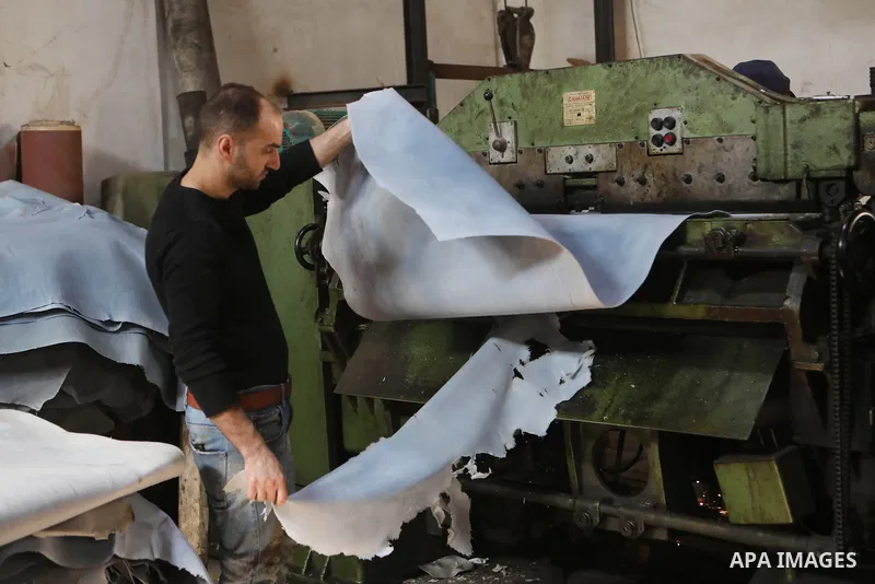 Palestinian workers paint leather and putting pieces out to dry as part of the finish process of leather tanning in a small factory to sell it to manufacture of shoes, in the West Bank city of Hebron on October 27, 2021....