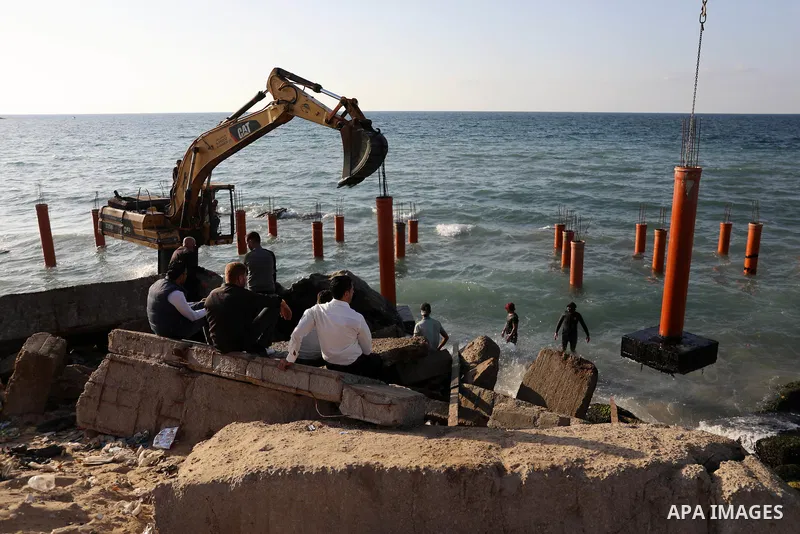 Palestinian workers operate a bulldozer to set up stilts in the Mediterranean sea to build a coffee shop at the Gaza city beach, using simple materials availabe in the besieged Gaza Strip, on October 27, 2021. Photo by M...