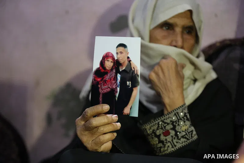 The mother of Palestinian prisoner Sami al-Amour who dead in Israeli Jails as a result of intentional medical negligence holds his photos in Deir al-Balah in the center of Gaza strip on November 18, 2021. The al-Amour, 3...