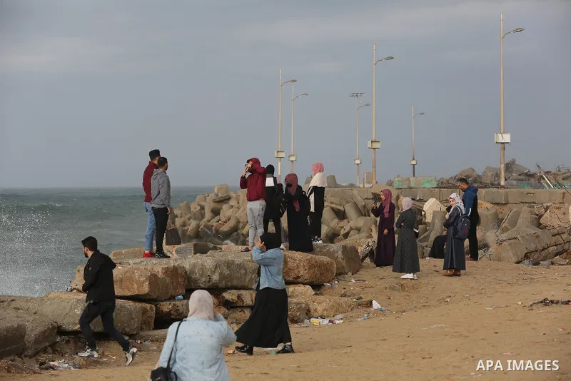 Palestians enjoy during a rainy day, at a beach in Gaza City 20 November 2021. A low pressure front is expected to affect Palestine today causing temperature to plummet and approach 7°C below the seasonal average and pav...