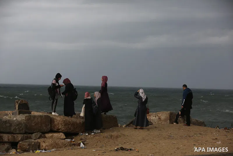 Palestians enjoy during a rainy day, at a beach in Gaza City 20 November 2021. A low pressure front is expected to affect Palestine today causing temperature to plummet and approach 7°C below the seasonal average and pav...