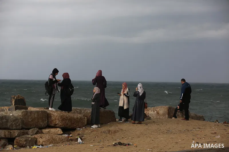 Palestians enjoy during a rainy day, at a beach in Gaza City 20 November 2021. A low pressure front is expected to affect Palestine today causing temperature to plummet and approach 7°C below the seasonal average and pav...