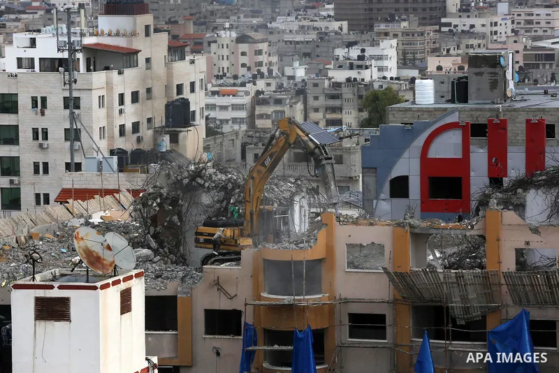Palestinian workers remove the rubbles of al-Jawhara tower which was hit by Israeli strikes during the recent 11-day conflict between Israel and Hamas on May, in Gaza city on November 21, 2021. Photo by Ashraf Amra