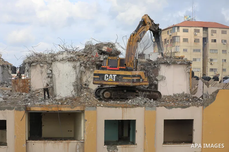 Palestinian workers remove the rubbles of al-Jawhara tower which was hit by Israeli strikes during the recent 11-day conflict between Israel and Hamas on May, in Gaza city on November 21, 2021. Photo by Ashraf Amra