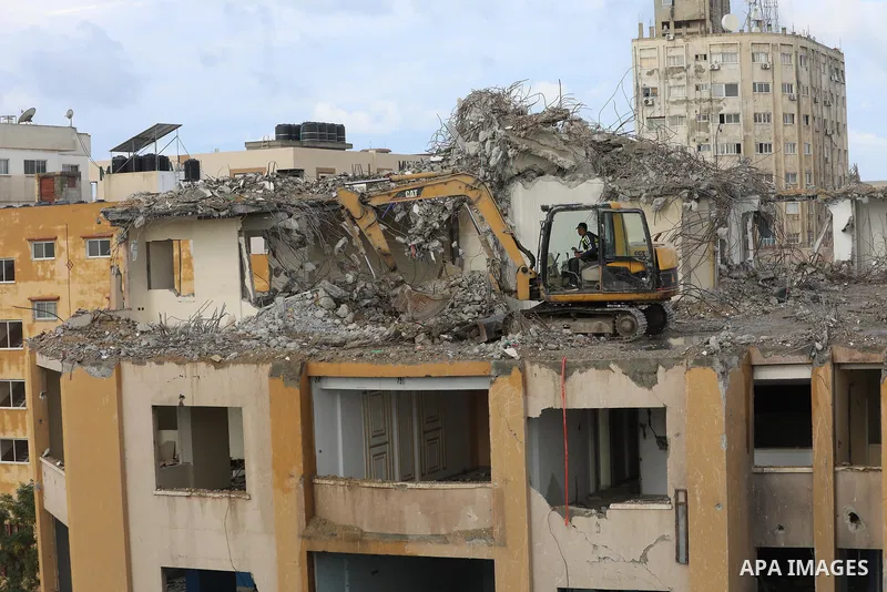 Palestinian workers remove the rubbles of al-Jawhara tower which was hit by Israeli strikes during the recent 11-day conflict between Israel and Hamas on May, in Gaza city on November 21, 2021. Photo by Ashraf Amra