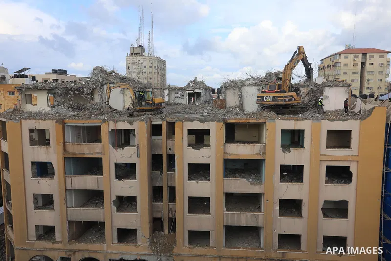 Palestinian workers remove the rubbles of al-Jawhara tower which was hit by Israeli strikes during the recent 11-day conflict between Israel and Hamas on May, in Gaza city on November 21, 2021. Photo by Ashraf Amra